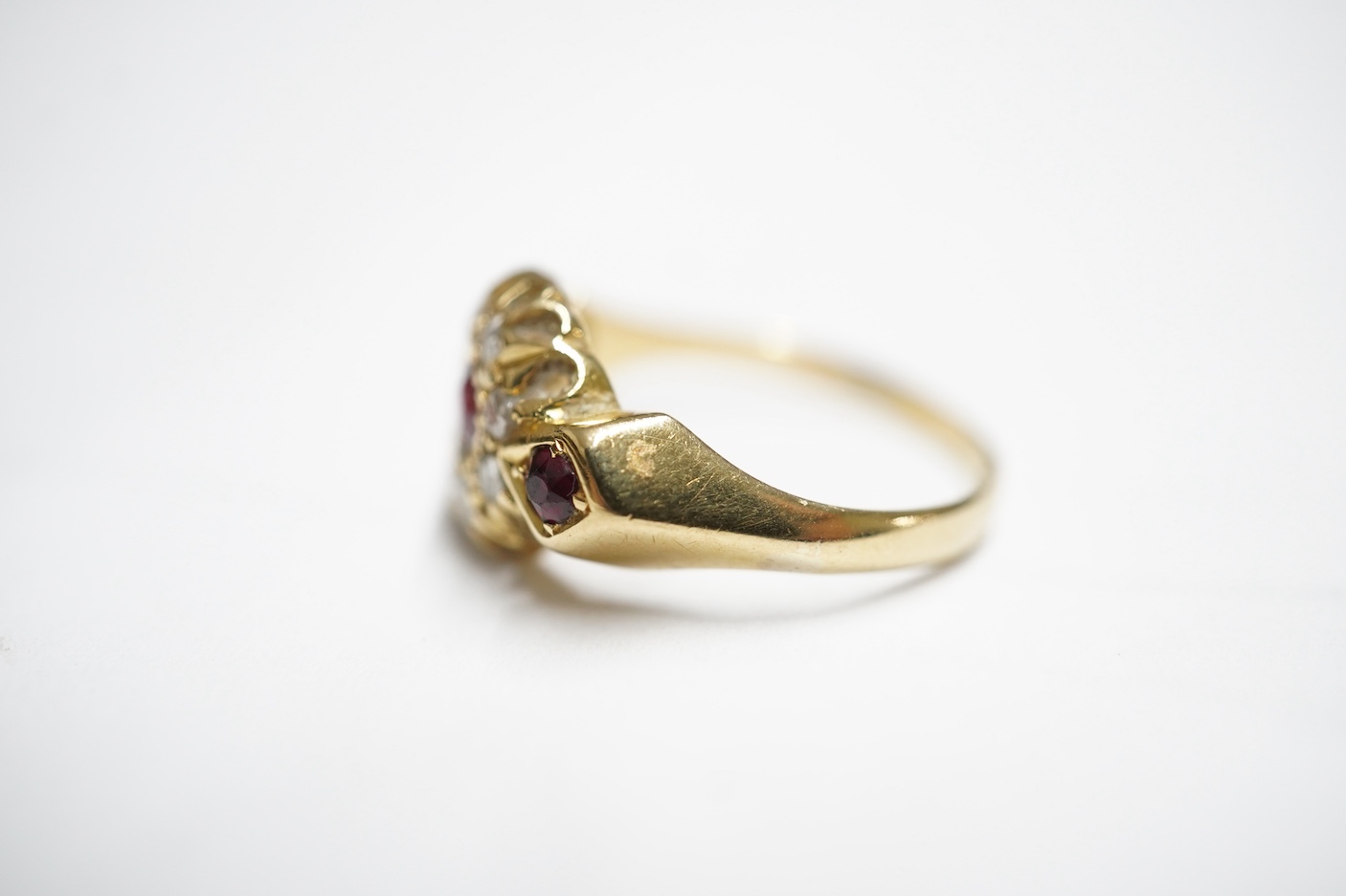 An early 20th century yellow metal and three stone ruby set ring, the centre stone bordered with rose cut diamonds, size H/I, gross weight 2.8 grams.